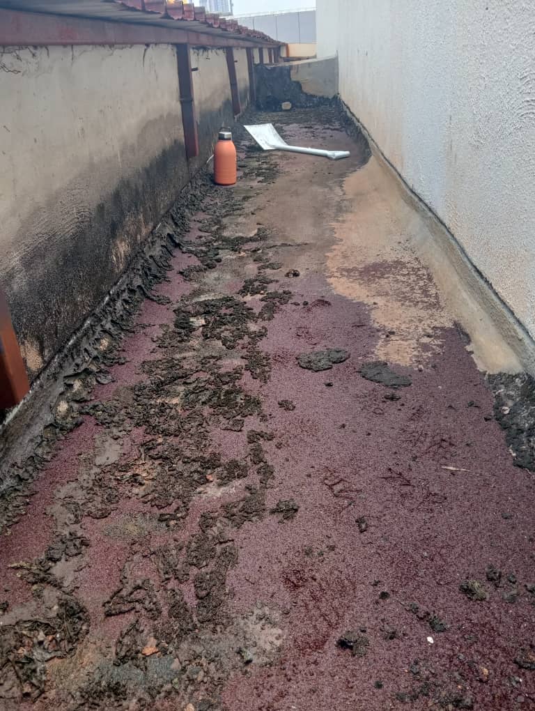 Ground-level concrete drainage channel with severely flaking waterproof coating exposing bare concrete