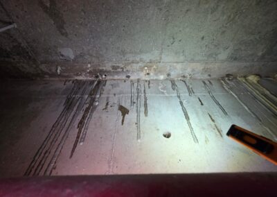 Close-up of a concrete slab soffit with drilled injection ports and polyurethane resin actively seeping through during PU injection repair