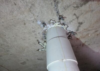 Cured polyurethane resin sealing an injection port around a pipe penetration point in a concrete slab