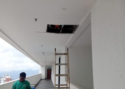 Vseal technician operating a PU injection pump on a condominium corridor ceiling