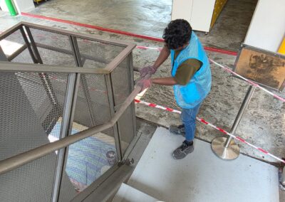 Technician sanding rust off a metal staircase handrail down to bare metal before repainting