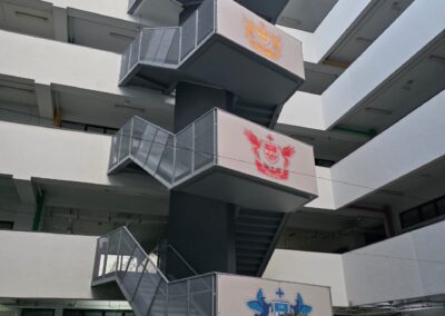 Refurbished exterior metal fire escape staircase with school house-crest emblems at an international school in Subang