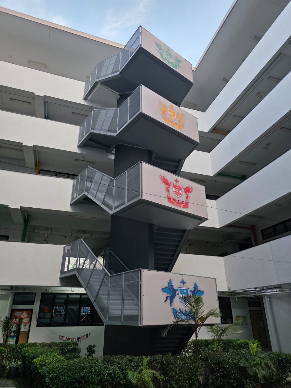 Refurbished exterior metal fire escape staircase with school house-crest emblems at an international school in Subang
